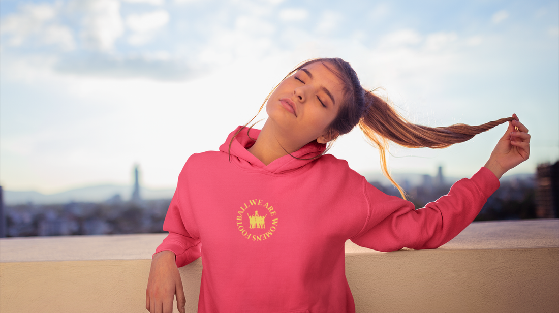 Young female football fan wearing a Women’s Football hoodie and fan merch, celebrating the women’s game.