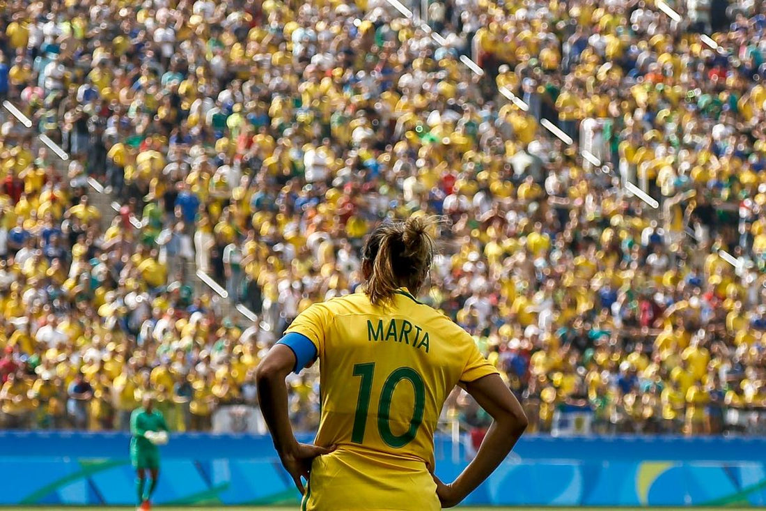Brazilian footballer Marta wearing number 10 shirt, standing on the pitch in front of a large crowd of fans